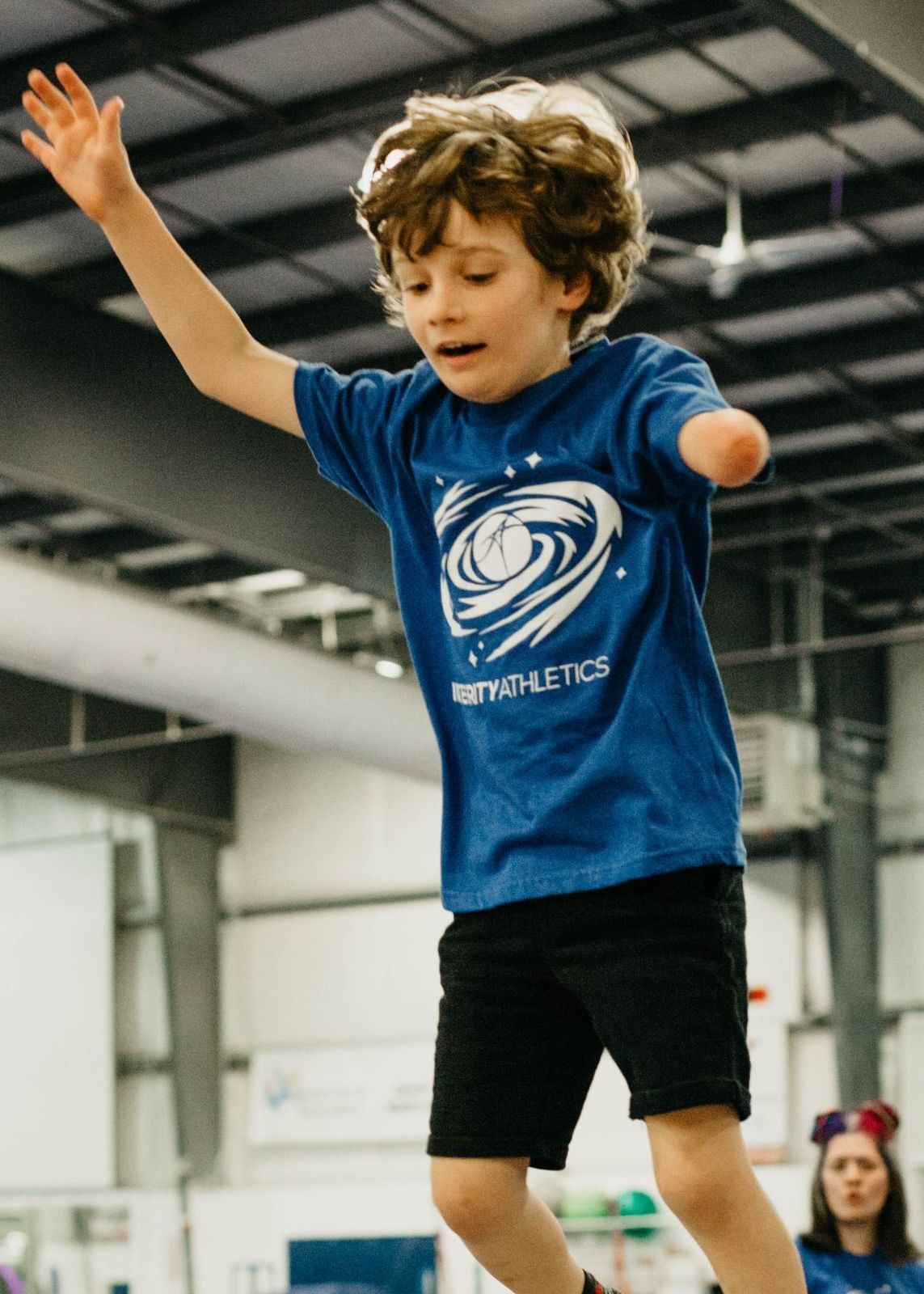 A young boy in a blue shirt is jumping in the air
