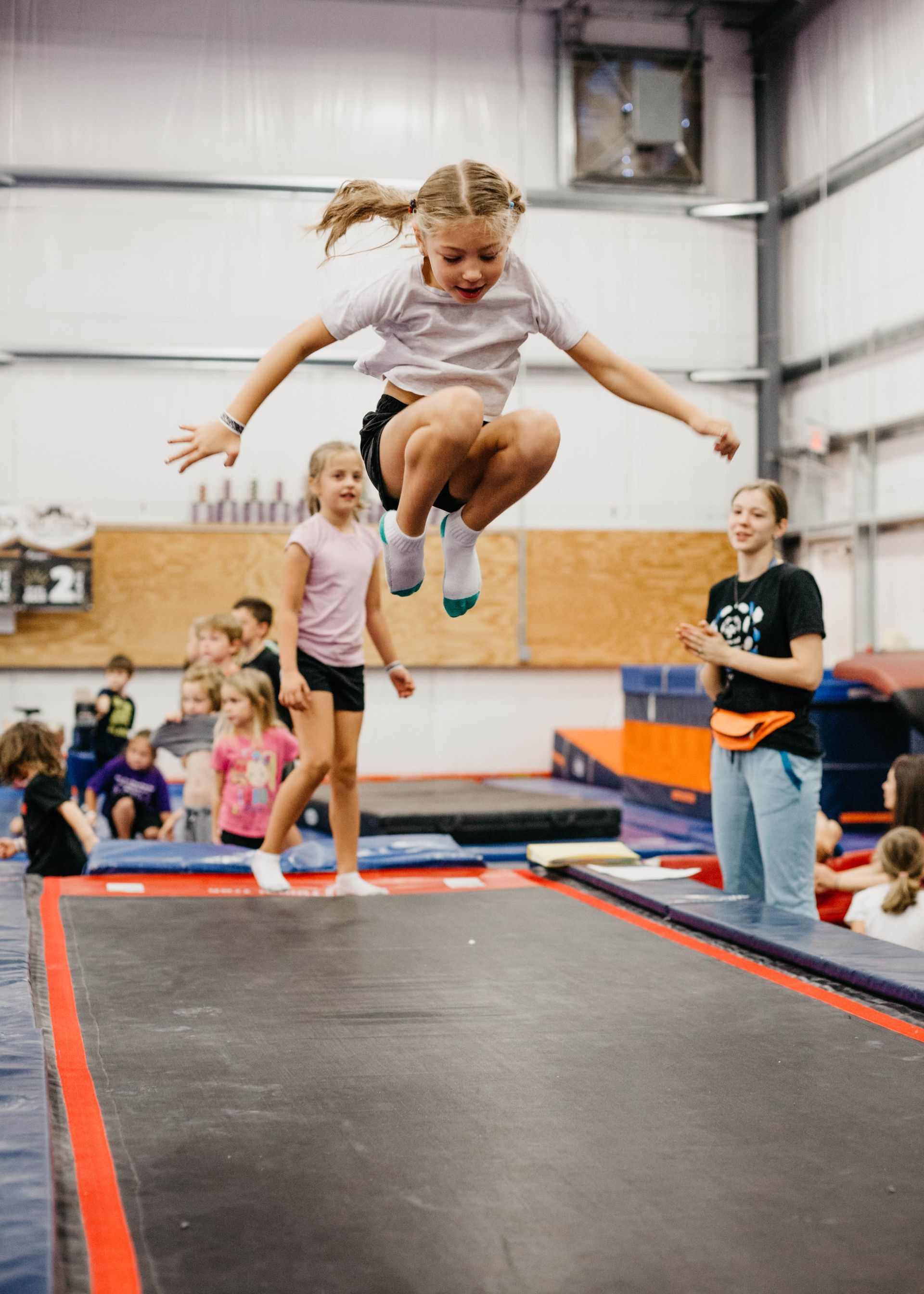 A young girl is jumping on a trampoline in a gym.