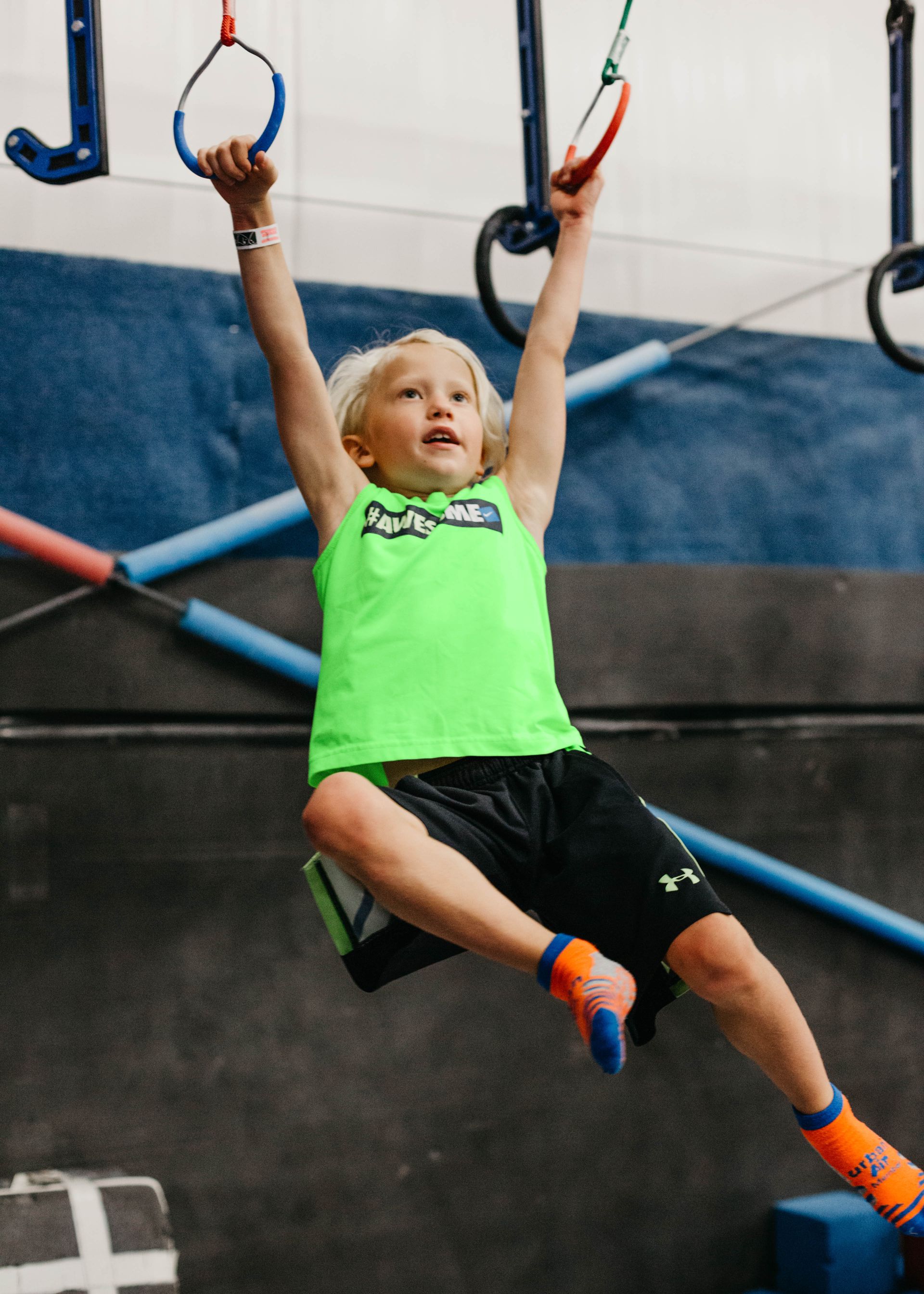 child in green shirt playing on gym equipment