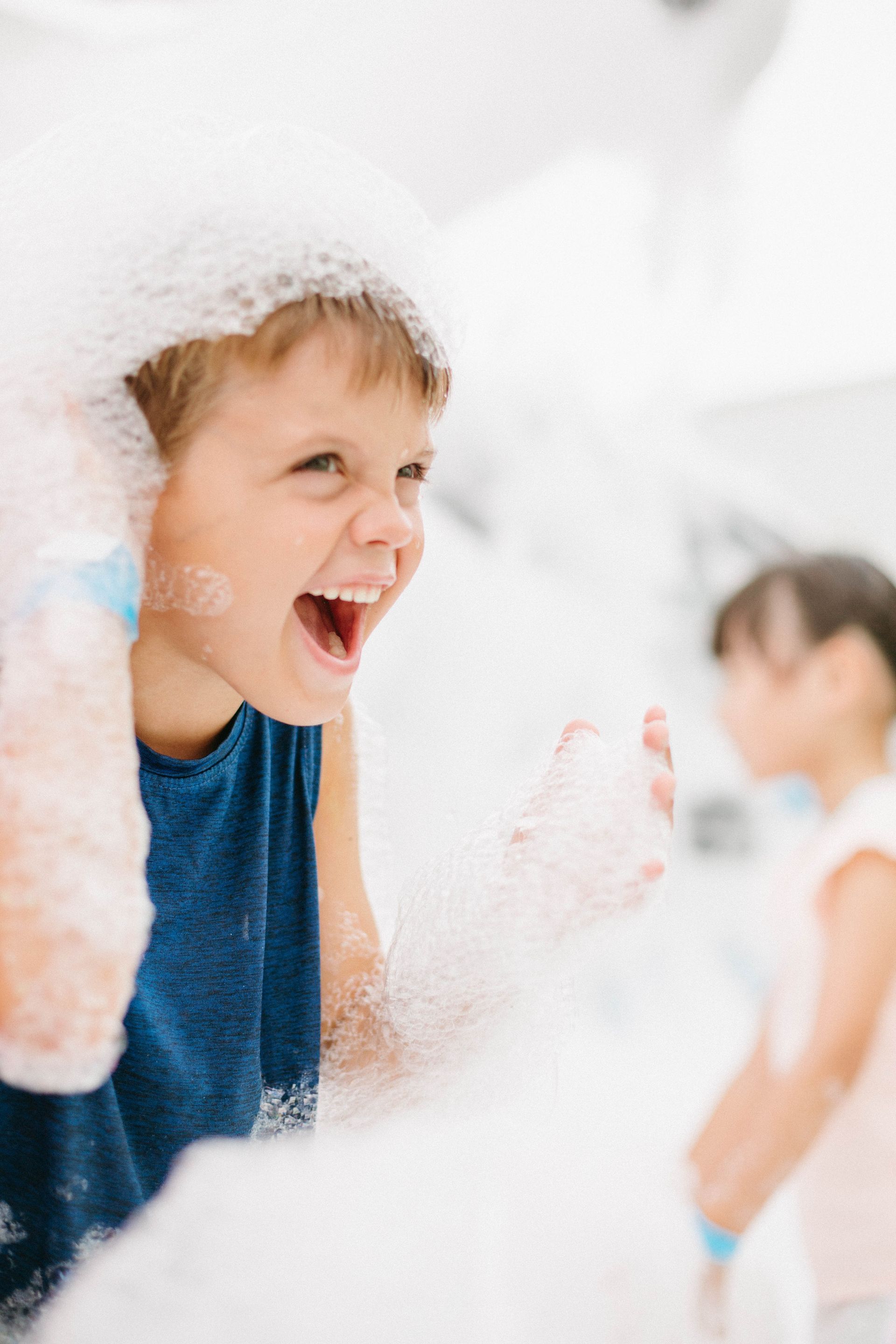 A young boy is playing with soap bubbles in a room.