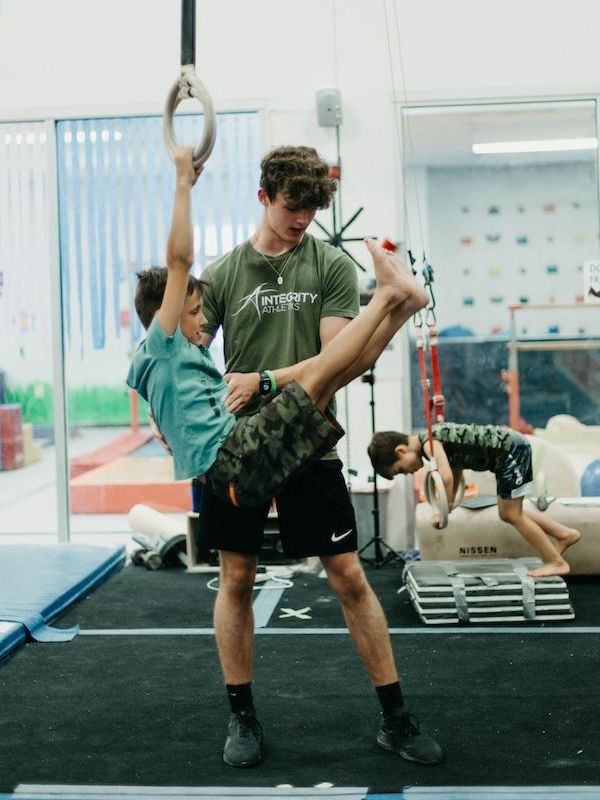 A man is holding a young boy in his arms in a gym.