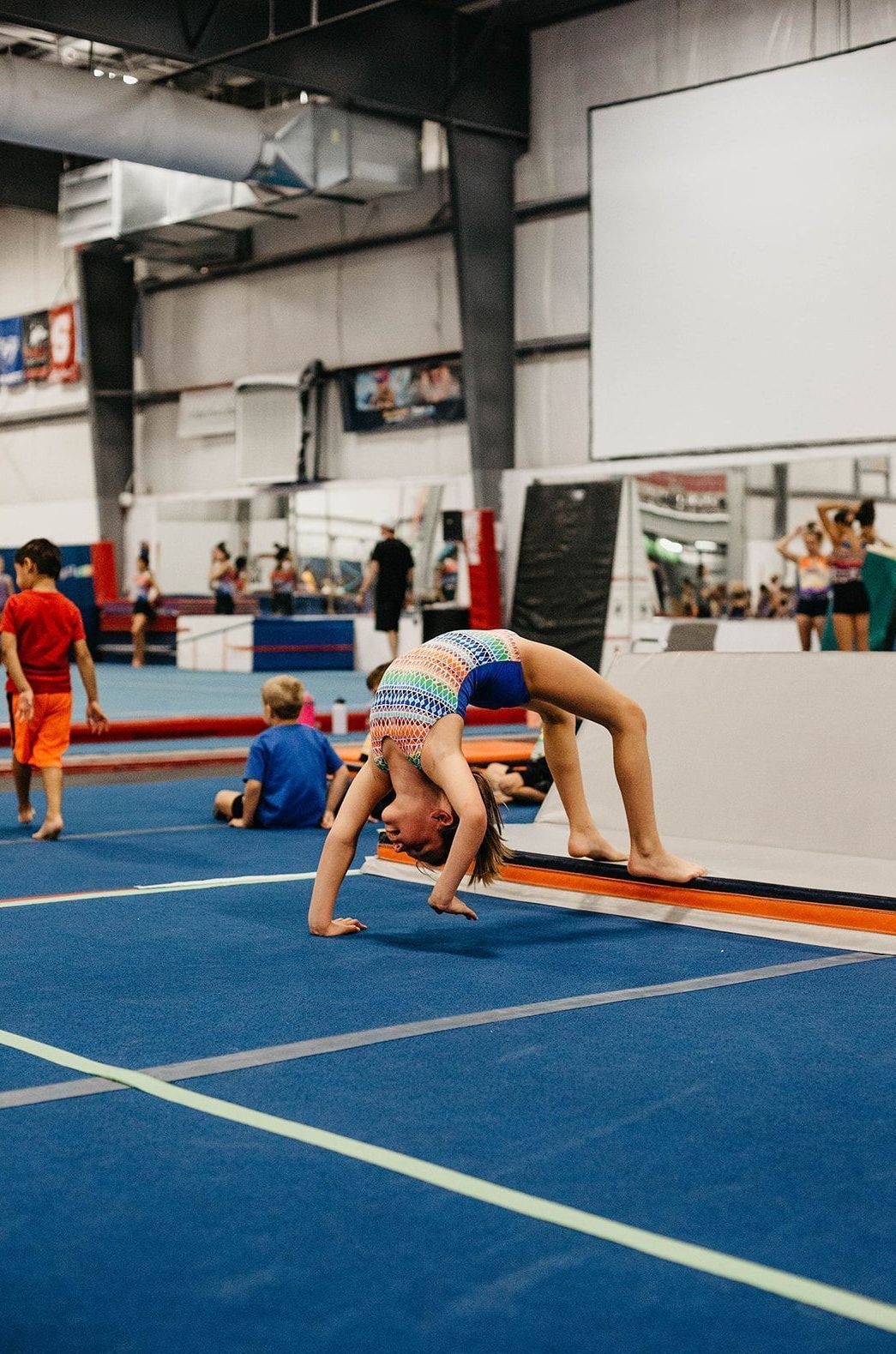 A young girl is doing a handstand on a gym floor.
