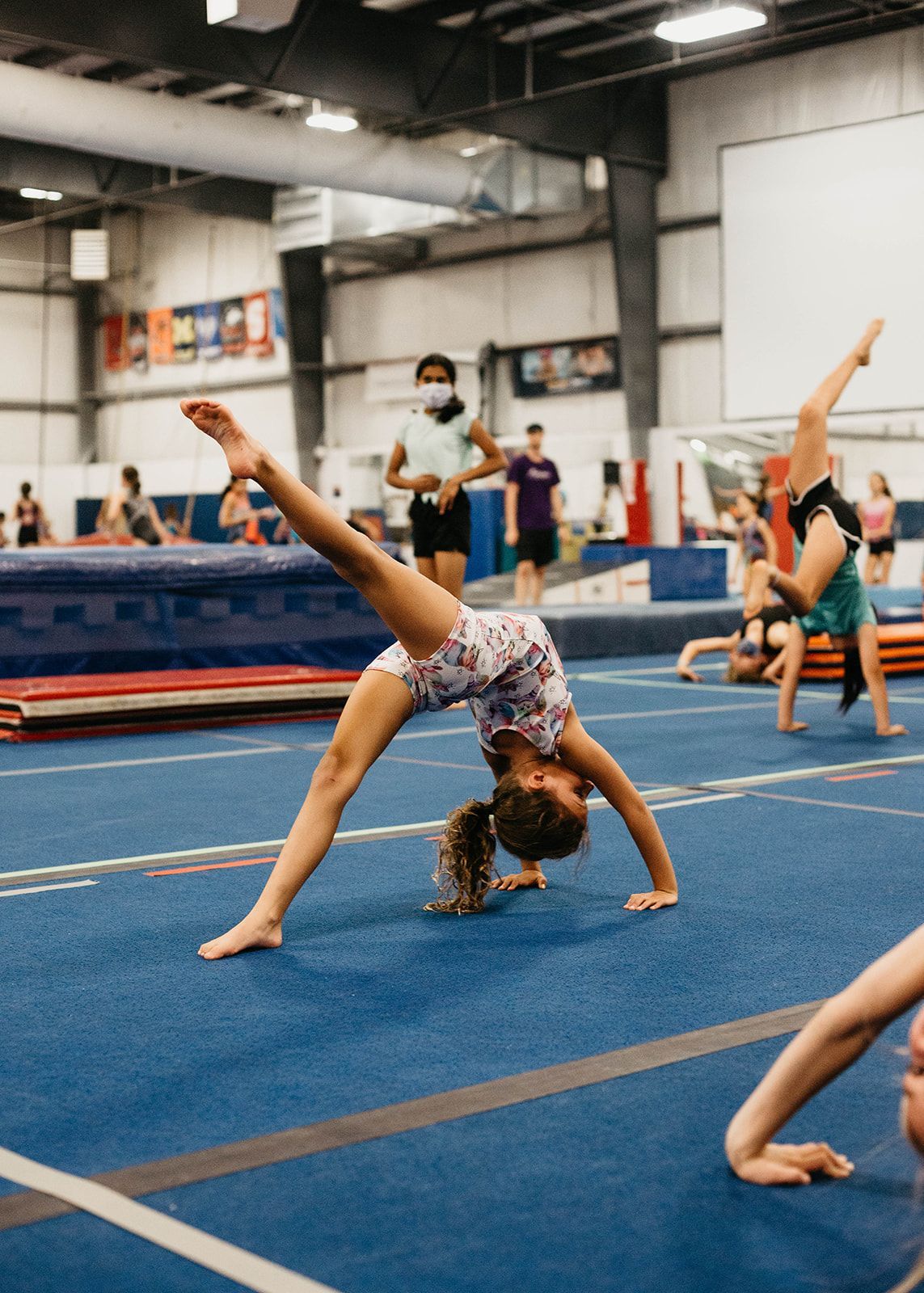 A girl is doing a handstand on a gym floor.