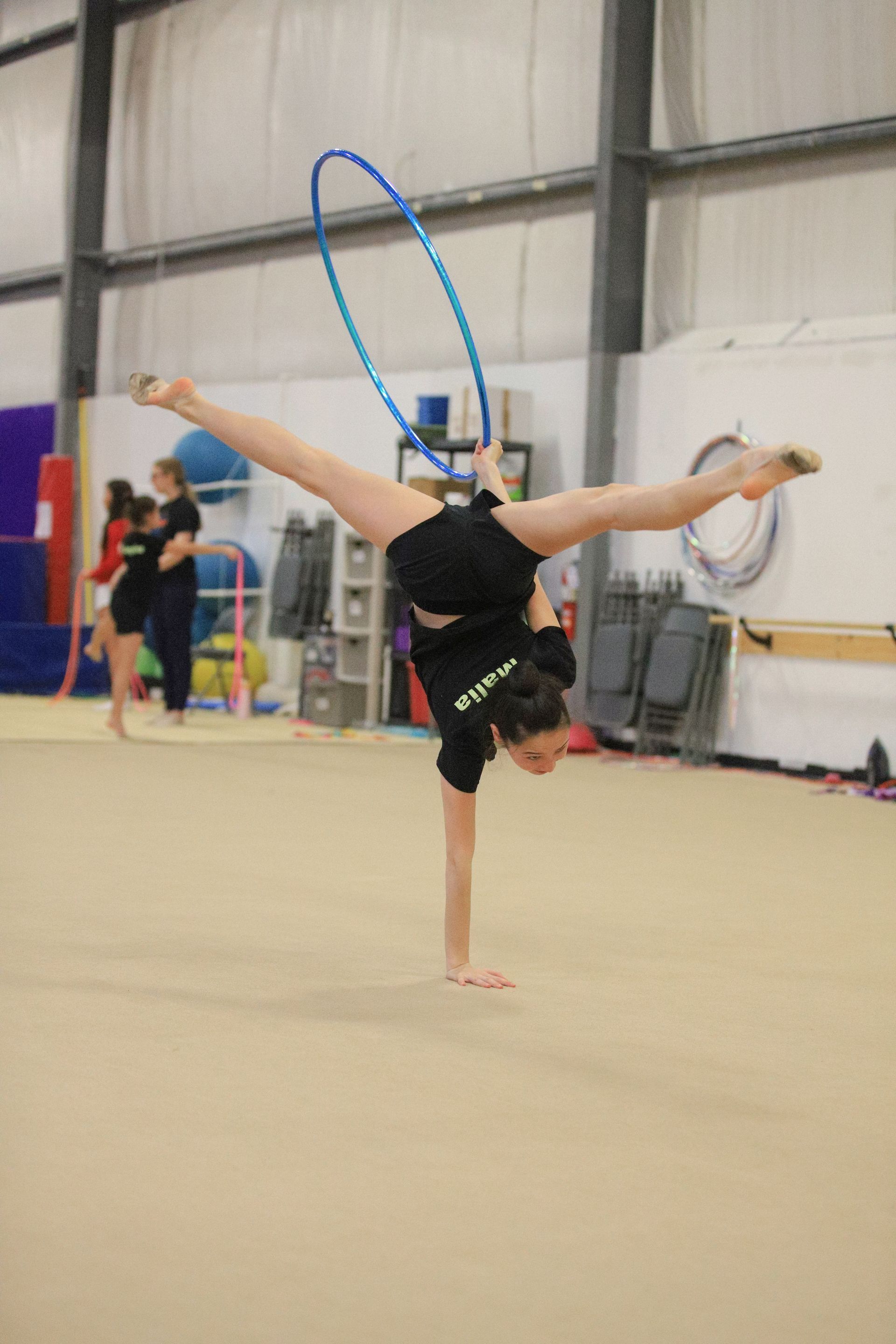 A young girl is doing a handstand with a hula hoop.