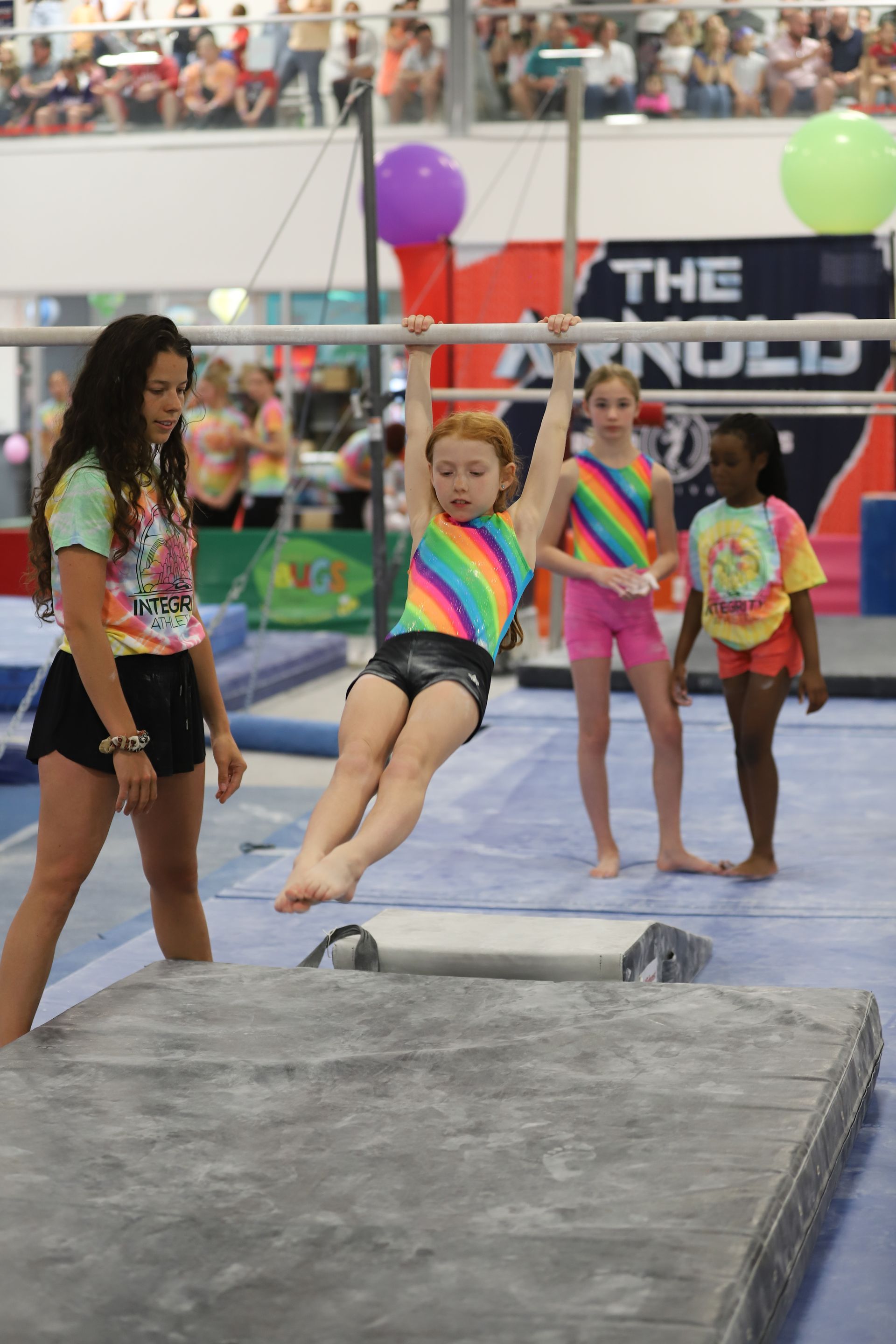 A young girl is jumping on a trampoline in a gym.