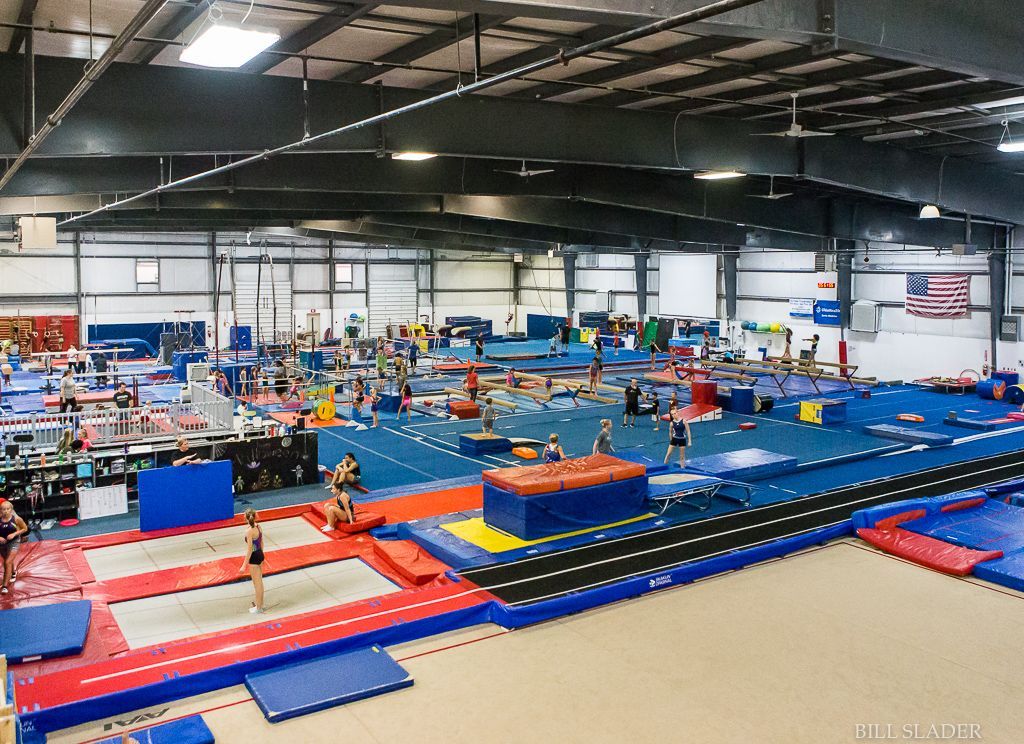 A large gym filled with people doing gymnastics.