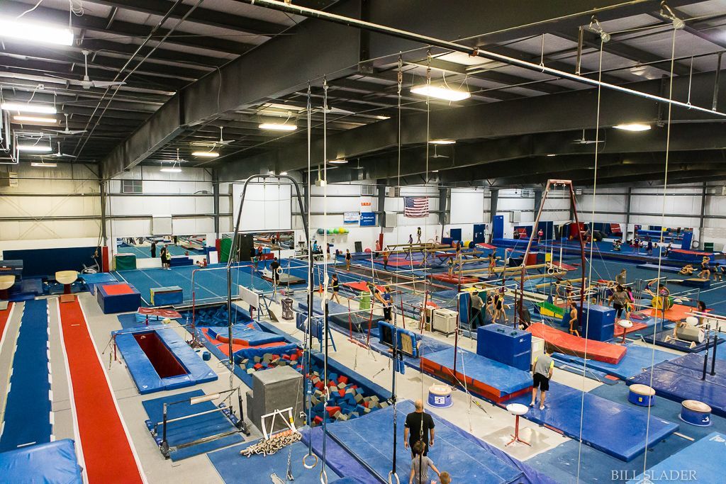 A large gym filled with lots of equipment and people doing gymnastics.