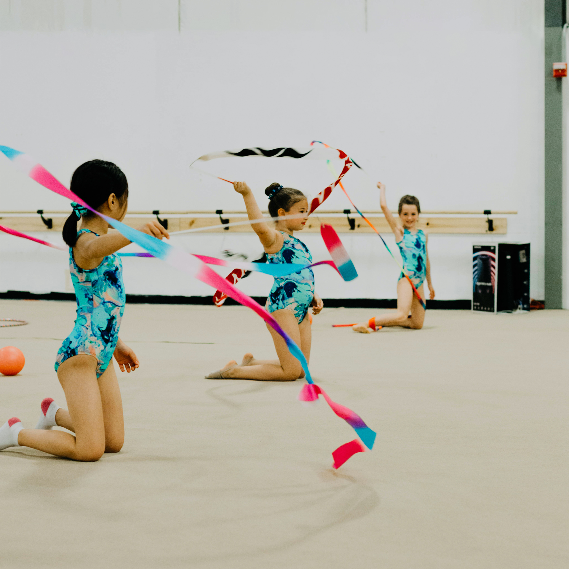 A group of young girls are practicing rhythmic gymnastics with ribbons