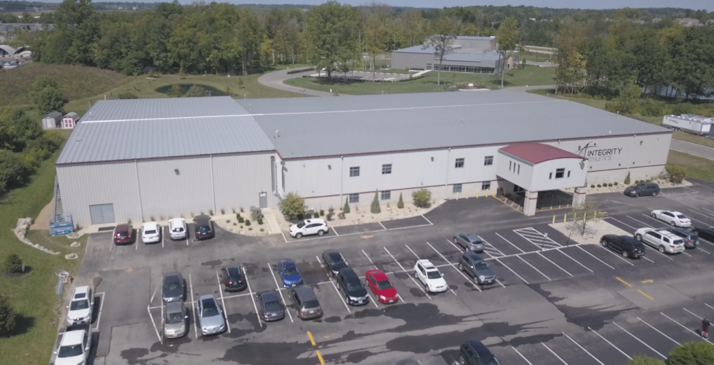 An aerial view of a large building with a lot of cars parked in front of it.