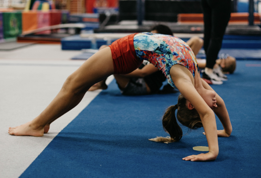 A young girl is doing a handstand on a blue mat.