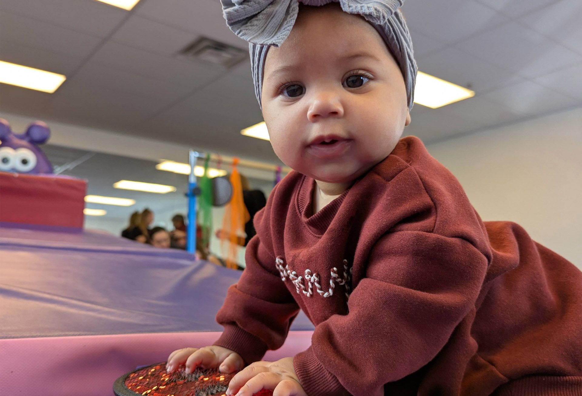 A little girl is standing on a trampoline in a gym.