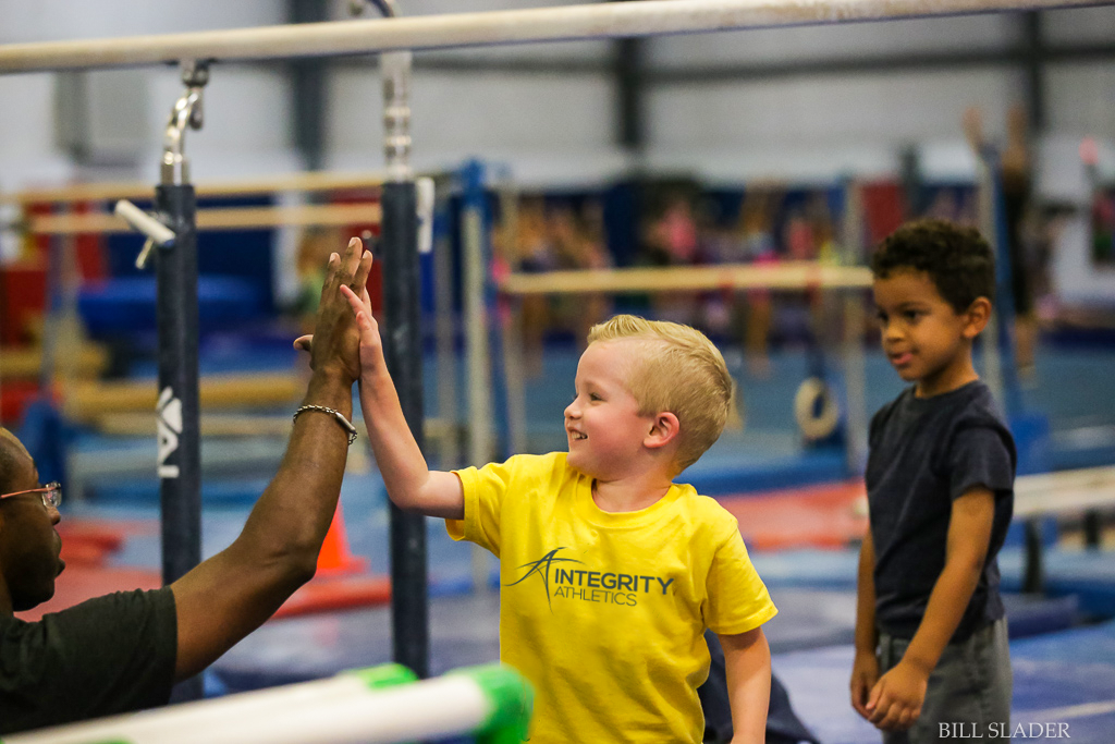 A man is giving a young boy a high five in a gym.