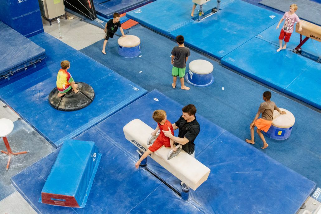 A group of children are doing gymnastics in a gym.