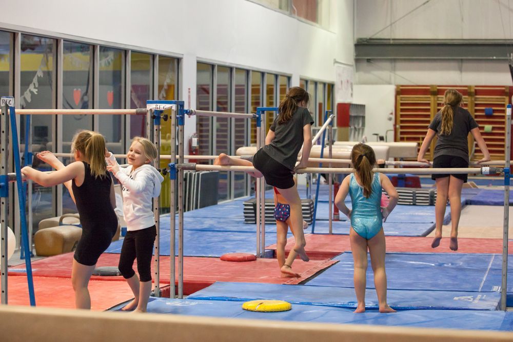 A group of young girls are doing gymnastics in a gym.