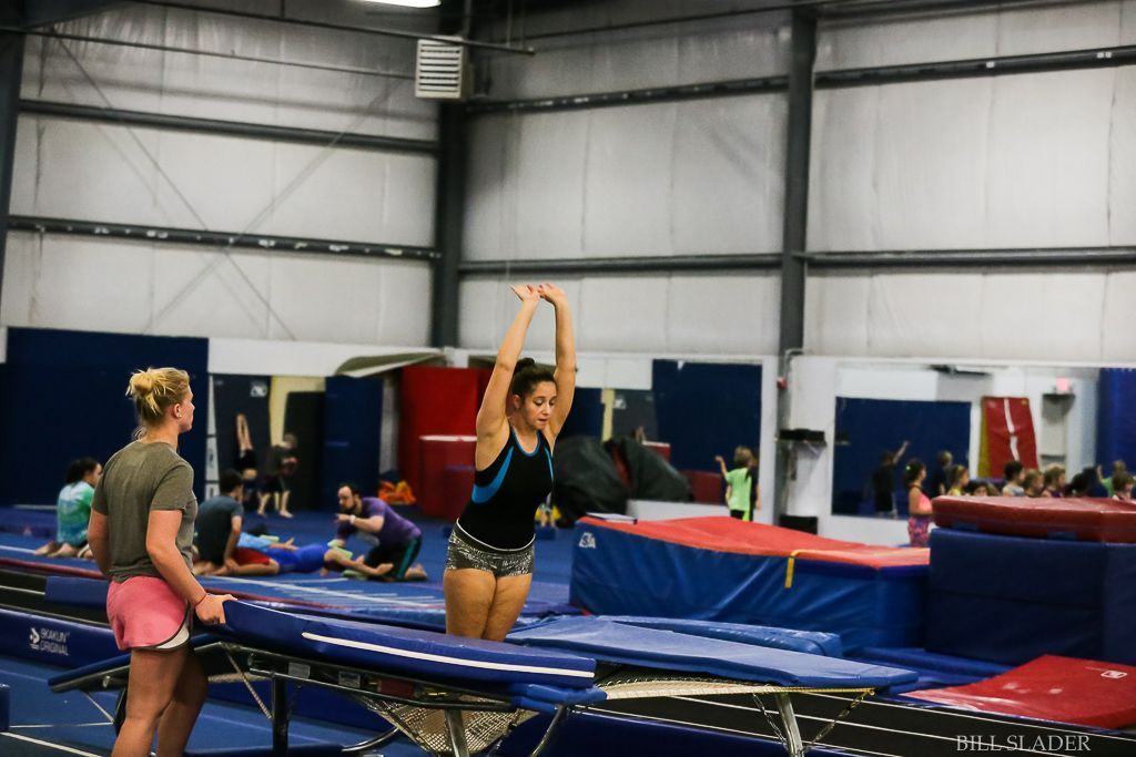 A woman is doing a trick on a trampoline in a gym