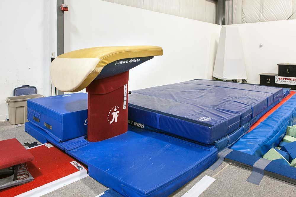 A gym with a vault and a balance beam.