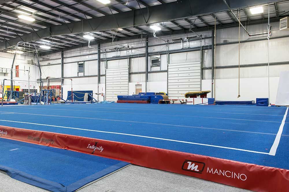 A large indoor gym with a blue mat and a red padding.