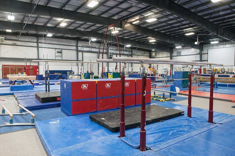 A gym with a blue mat and red and blue bars.