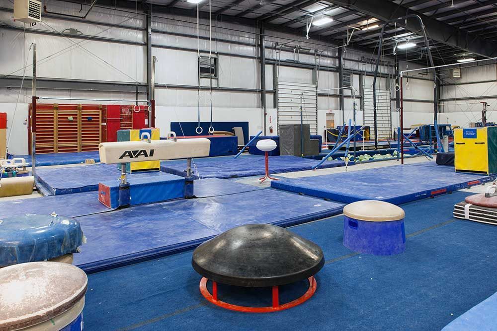 A gym filled with a lot of equipment including a balance beam