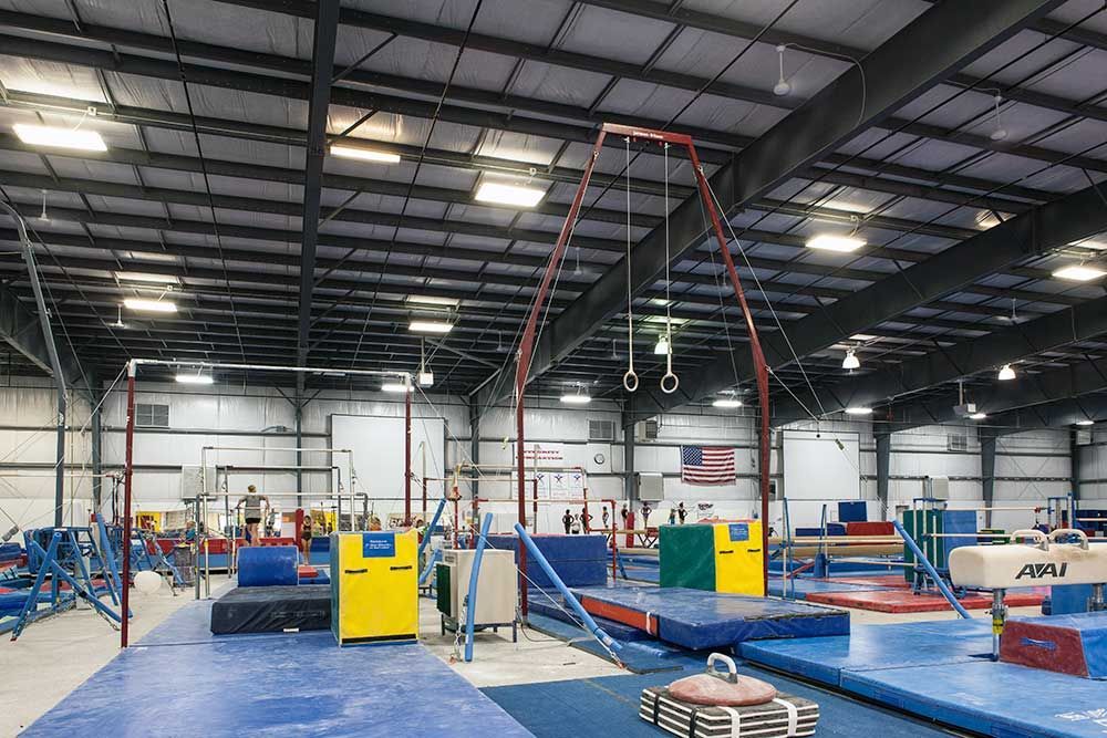 A large gym filled with a variety of gymnastics equipment.