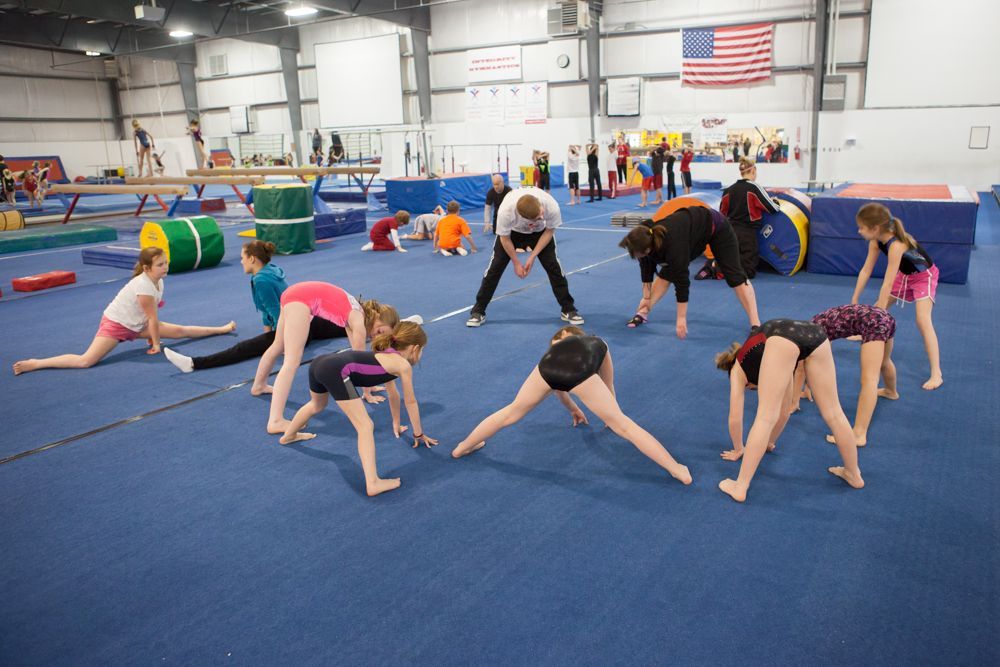 A group of young girls are doing stretching exercises in a gym.