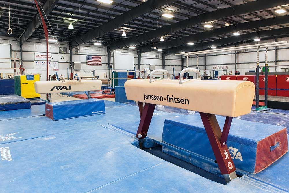A gym with a pommel horse in the middle of it.