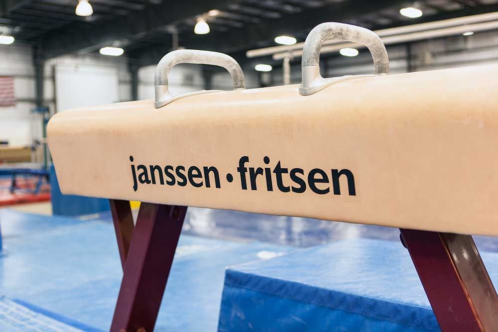 A janssen fritsen pommel horse is in a gym.
