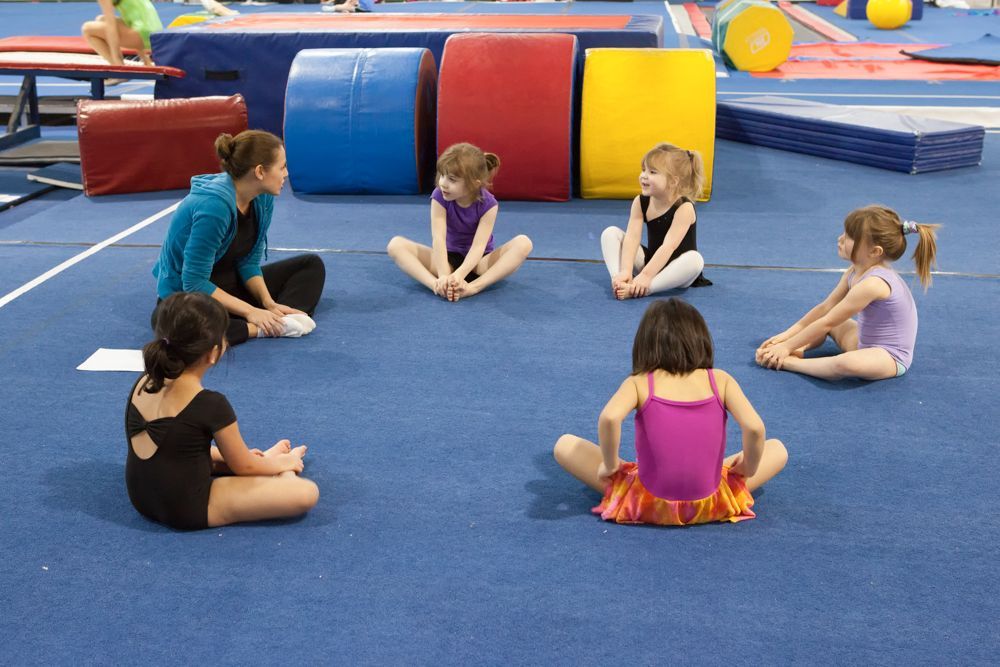 A group of young girls are sitting in a circle on the floor