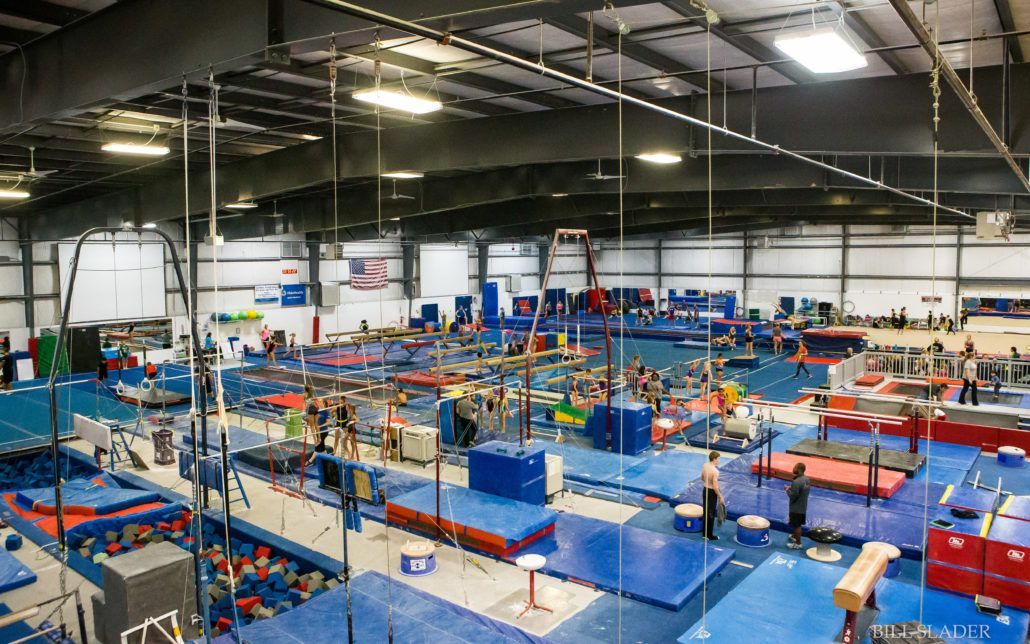 A large gym filled with lots of equipment and people doing gymnastics.