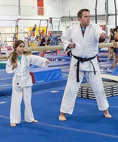 A man and a girl are practicing judo in a gym.