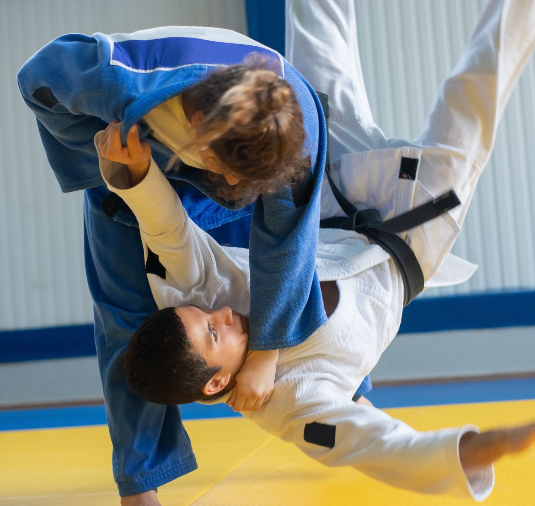 A man and a woman are practicing judo on a mat.