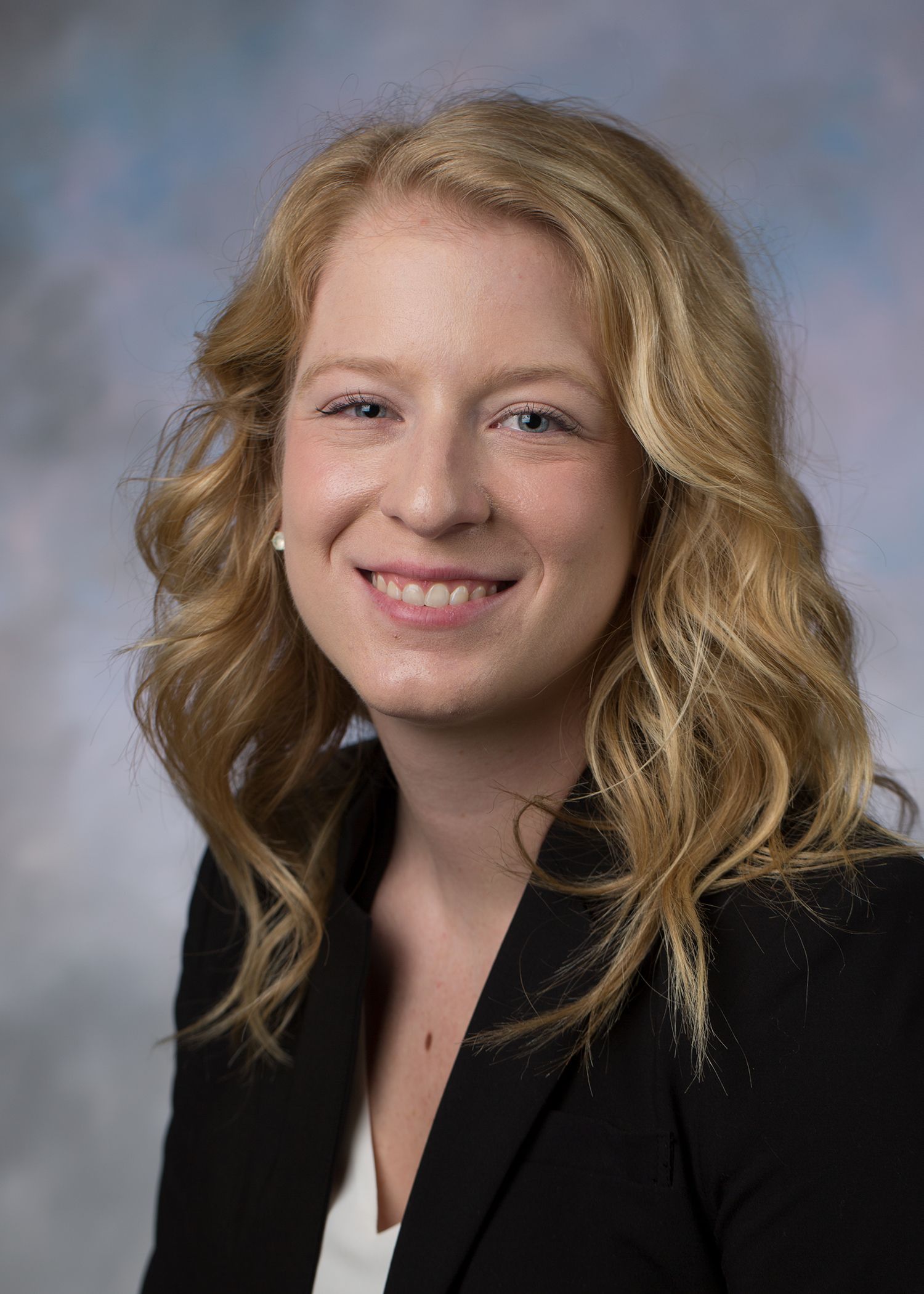 A woman in a black jacket and white shirt is smiling for the camera.