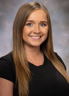 The woman is wearing a black shirt and smiling for the camera.