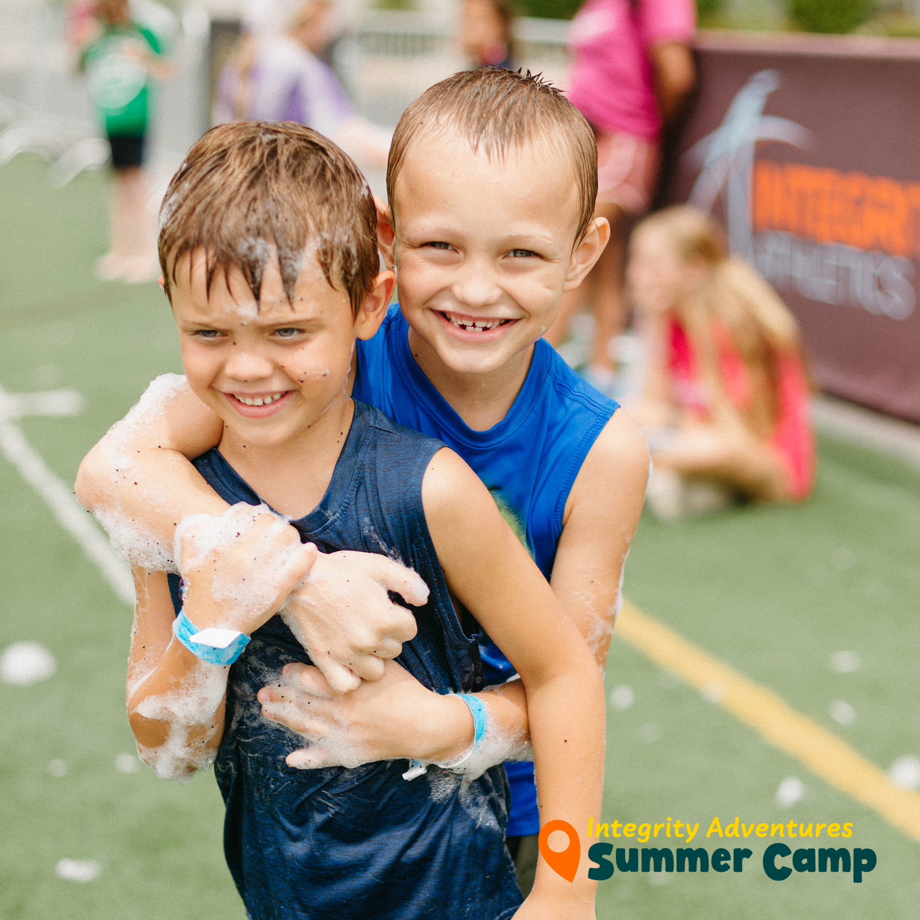 Two young boys hugging each other with integrity adventures summer camp written on the bottom