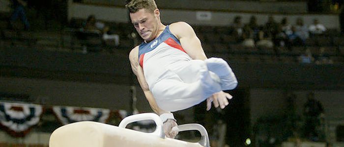 A gymnast is doing a trick on a pommel horse.