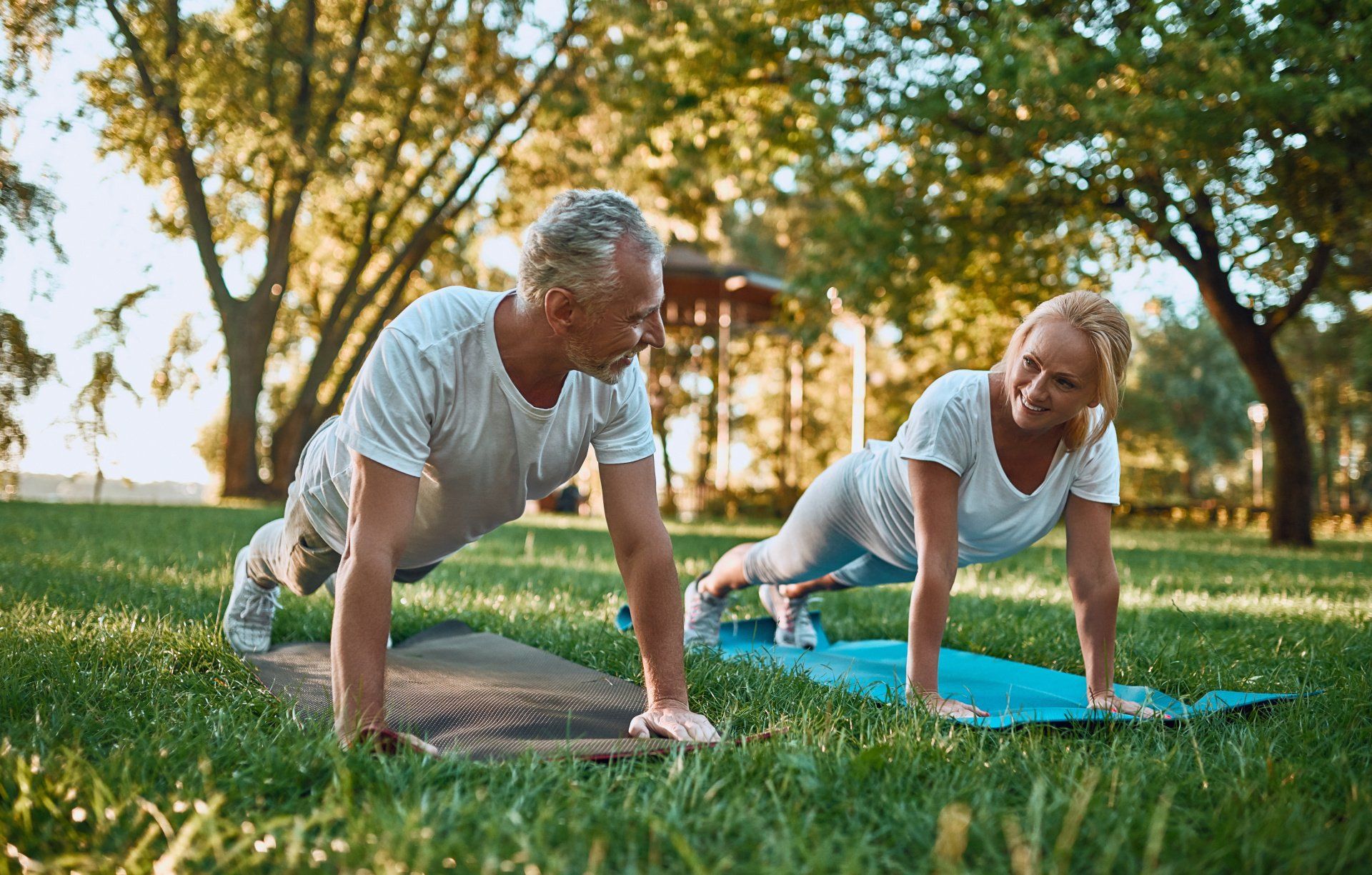 middle aged couple doing mat exercises at the park