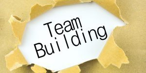 The word team building is coming out of a hole in a piece of paper.