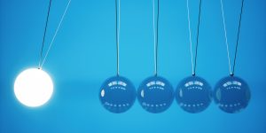 A newton 's cradle with a light bulb hanging from it.