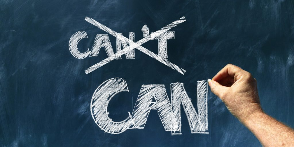 A person is writing on a blackboard that the word can is crossed out