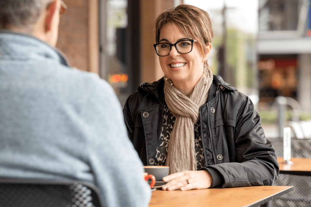 A woman is sitting at a table talking to a man.
