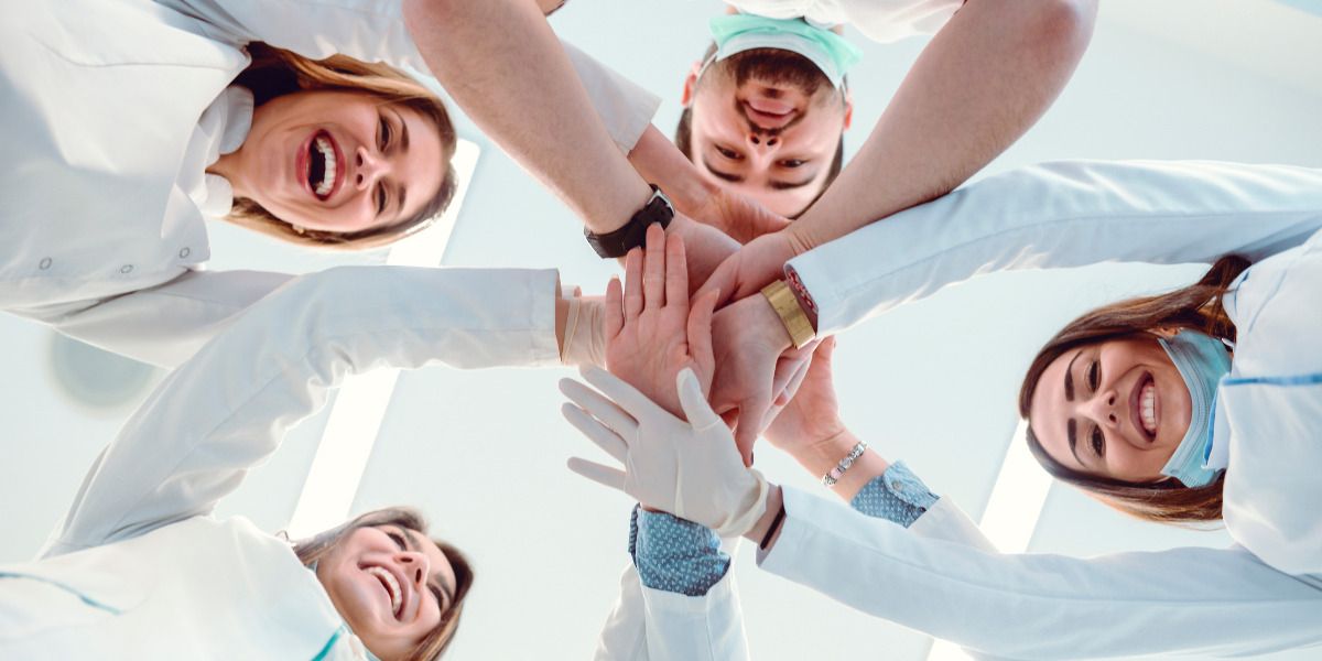 A group of dentists are putting their hands together in a circle.
