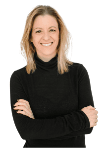 A woman in a black turtleneck is smiling with her arms crossed