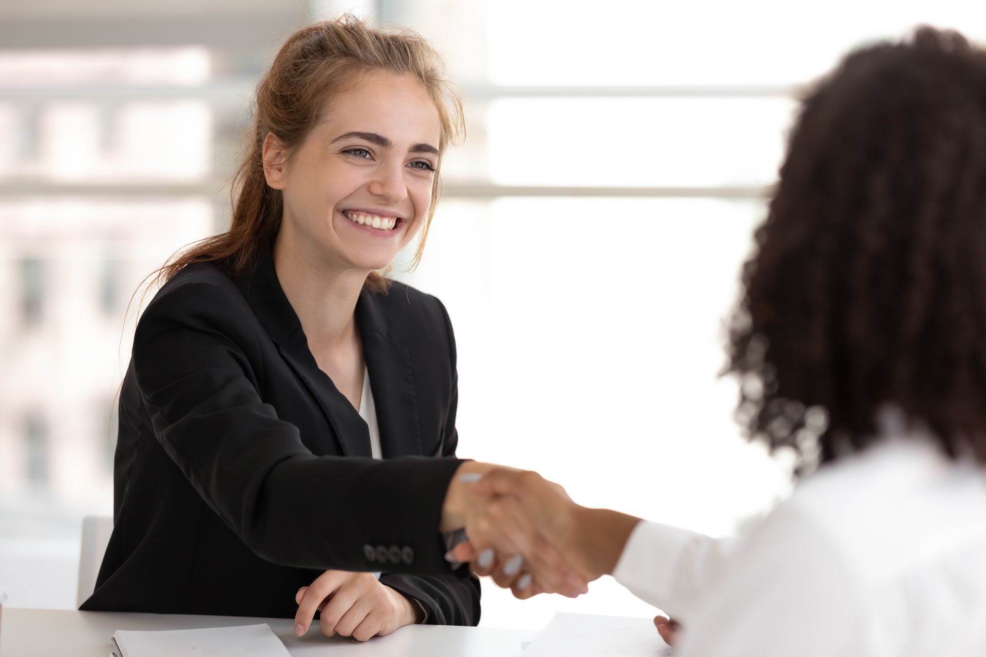 A woman is shaking hands with another woman during a job interview.