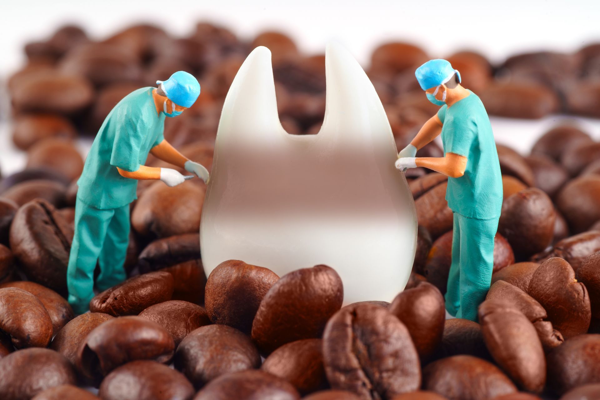Two dentists are working on a tooth in a pile of coffee beans