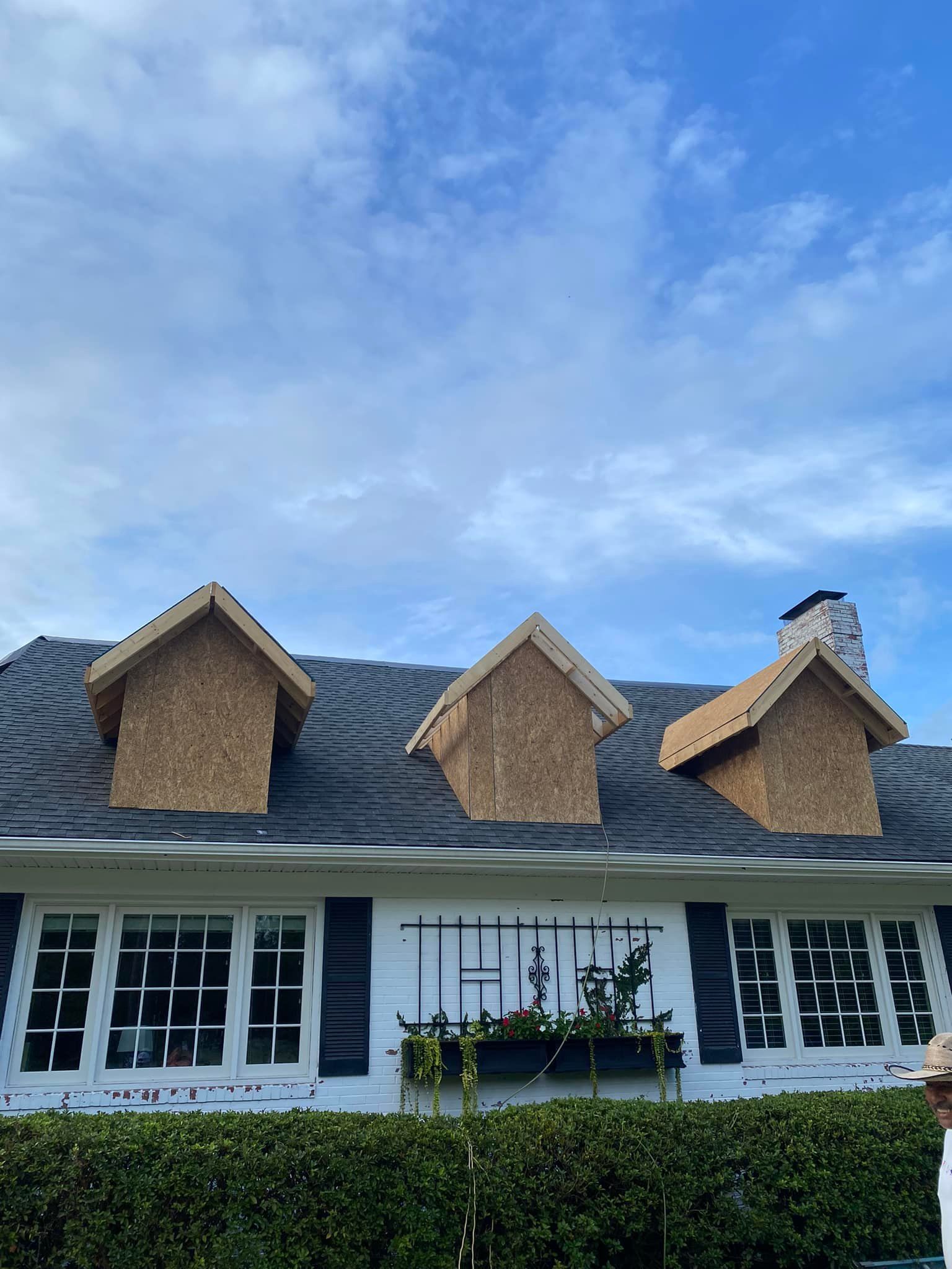 A man is standing in front of a house that is being remodeled.