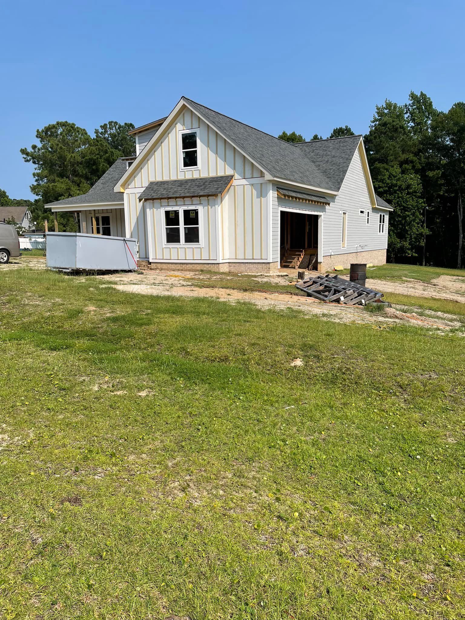 A white house is sitting on top of a lush green field.