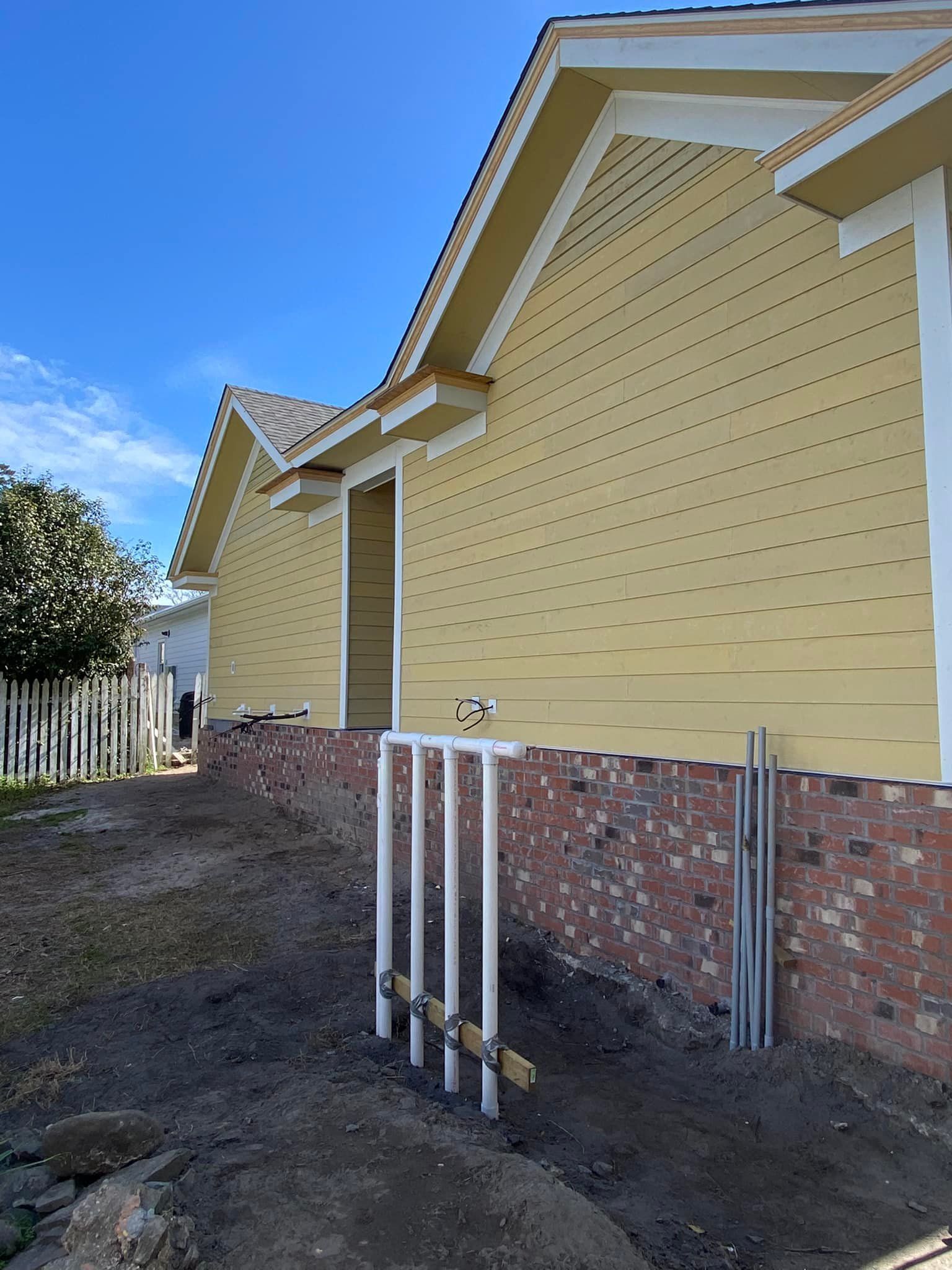A yellow house with a brick foundation is being built.