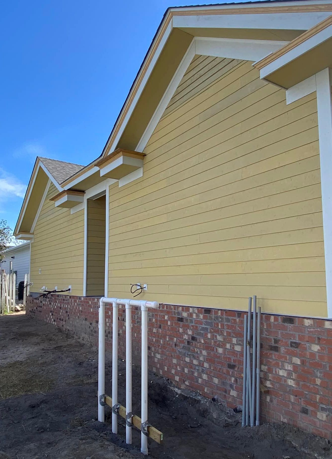 A yellow house with white trim is being built