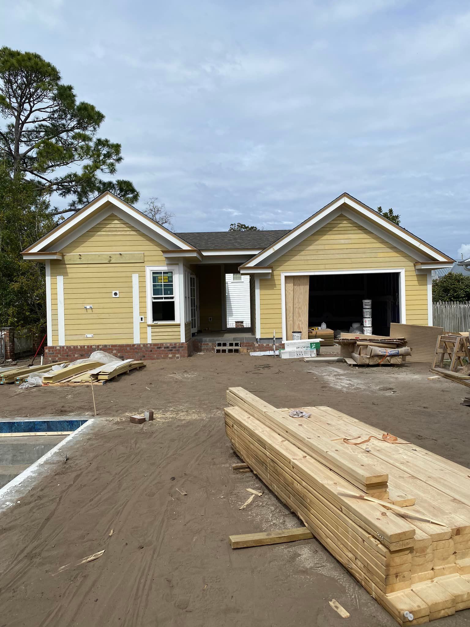 A yellow house is being built with wood in front of it.