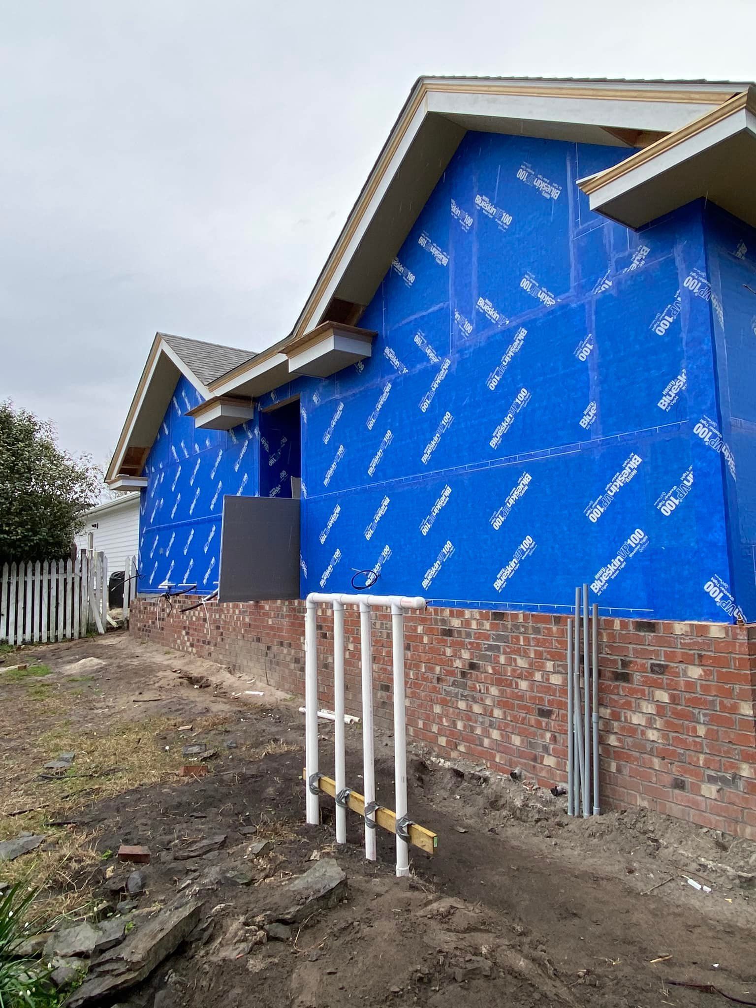 A house is being built with blue siding and a brick wall.